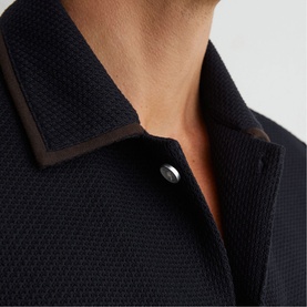 Reiss blue textured polo shirt close-up showing brown contrast collar trim and silver snap button detail