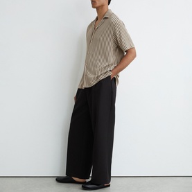 Model wearing Reiss beige striped short-sleeve shirt with black wide-leg trousers and black loafers.