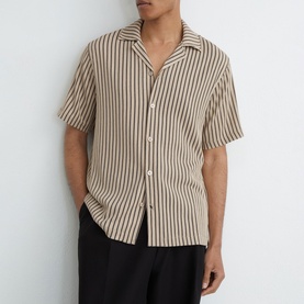 Model wearing Reiss beige striped short-sleeve shirt with Cuban collar, styled with black trousers