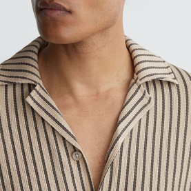 Model wearing Reiss beige stripe shirt, close-up of open camp collar and button placket detail