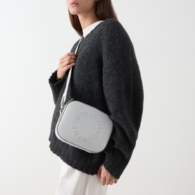 Model carrying Stella McCartney Logo Camera Crossbody Bag in Pearl Grey with silver-tone hardware and circular logo detail, worn crossbody