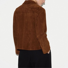 Model wearing a tan brown suede jacket, rear view, styled with black wide-leg trousers