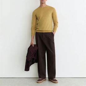 Model wearing Reiss yellow fine knit crew neck jumper with dark brown wide-leg trousers, carrying burgundy jacket