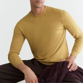 Model wearing Reiss yellow fine knit crew neck jumper, styled with dark trousers