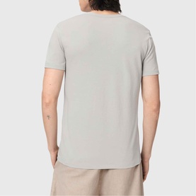 Model wearing All Saints Tonic Ramskull Logo T-Shirt in Pebble Grey, back view, short sleeves, styled with beige trousers.