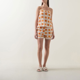 Model wearing Chelsea Peers Sunshine Tile Print Shorts Pyjama Set in Sunshine Grid, orange tile print cami and shorts, styled with white slider