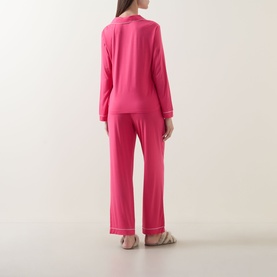 Model wearing Chelsea Peers Patch Pocket Long Pyjama Set in pink with contrast piping, shown from behind, paired with strappy sandals.