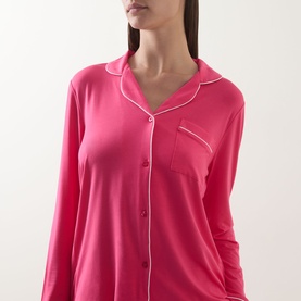 Model wearing Chelsea Peers Patch Pocket Long Pyjama Set in pink with white contrast piping, revere collar, front button fastening and chest patch