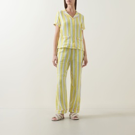 Model wearing Chelsea Peers Wiggle Stripe Cheesecloth Long Pyjama Set in yellow stripe, short-sleeve top and straight-leg trousers, styled with white