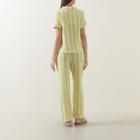 Model wearing Chelsea Peers Wiggle Stripe Cheesecloth Long Pyjama Set in yellow stripe, showing back view of short-sleeve shirt and straight-leg