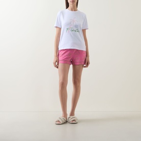 Model wearing Chelsea Peers Fiesta Graphic Print Shorts Pyjama Set in white tee with pink shorts, elasticated waistband and satin tie drawstring