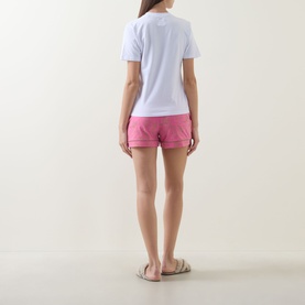 Model wearing Chelsea Peers Fiesta Graphic Print Shorts Pyjama Set, rear view, white tee and pink shorts with contrast piping, styled with slide