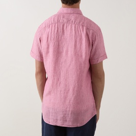 Model wearing Rodd & Gunn pink linen short-sleeve casual shirt, shown from the back, styled with navy trousers.