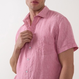 Model wearing Rodd & Gunn pink linen short-sleeve casual shirt with chest pocket and button placket, hand resting on collar