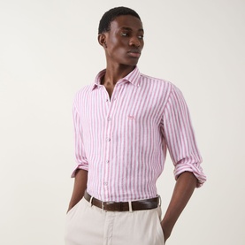 Model wearing Rodd & Gunn Seadown Stripe Shirt in RoseWater, pink stripe cotton, styled with white trousers and brown belt