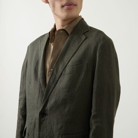 Model wearing Rodd & Gunn Campbell Island Single-Breasted Blazer in Dark Olive linen, showing notched lapels and button fastening, styled with brown