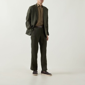 Model wearing Rodd & Gunn Campbell Island Single-Breasted Blazer in Dark Olive linen, styled with matching trousers, brown shirt and dark trainers.