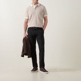 Model wearing Rodd & Gunn Oyster Island Striped Knitted Polo Shirt in Acorn, styled with black trousers and brown suede trainers, carrying a dark