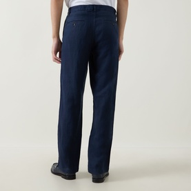 Model wearing Rodd & Gunn Spencer Bay Linen Trousers in navy, shown from behind, with rear buttoned jet pockets and belt loops visible.