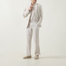 Model wearing Rodd & Gunn Spencer Bay Linen Trousers in Oatmeal, styled with a matching linen blazer and shirt, suede desert boots.