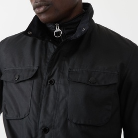 Model wearing Barbour black wax cotton casual jacket, close-up showing chest pockets and zip-up collar detail
