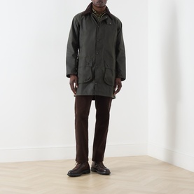 Model wearing Barbour green waxed cotton casual jacket, styled with brown trousers and dark leather shoes
