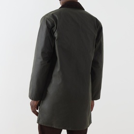 Model wearing Barbour green waxed cotton casual jacket, shown from the back with brown corduroy collar detail visible.