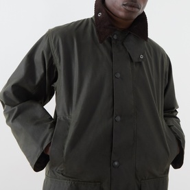 Model wearing Barbour green waxed cotton casual jacket with corduroy collar, hands in pockets