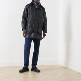 Model wearing Barbour navy waxed cotton casual jacket with blue jeans and black boots