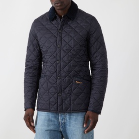 Model wearing Barbour navy quilted casual jacket with corduroy collar, styled with light blue jeans.