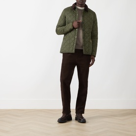 Model wearing Barbour Liddesdale Short Quilted Jacket in Olive with corduroy collar, styled with brown trousers and black boots.