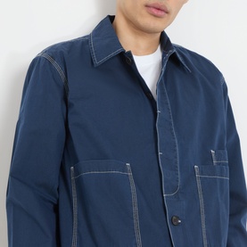Model wearing Farah Vintage Mattison Denim Jacket in Aegean Blue, with contrast white stitching, pointed collar and front pockets, over a white tee.