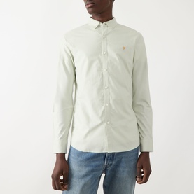Model wearing Farah Vintage Brewer Logo Shirt in Soft Green, long sleeves, button-down collar, styled with blue jeans.