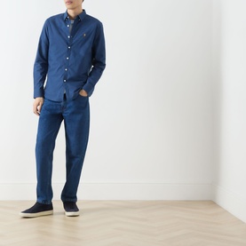 Model wearing Farah Vintage Brewer Logo Shirt in Aegean Blue, long sleeve button-down, styled with matching blue trousers and navy shoes.
