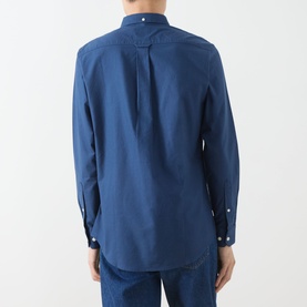 Model wearing Farah Vintage Brewer Logo Shirt in Aegean Blue, rear view showing back pleat, long sleeves, and button cuffs, styled with blue jeans.