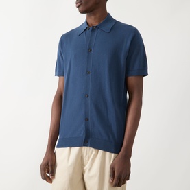 Model wearing Farah Vintage Poplar Knitted Polo Shirt in Aegean Blue, short sleeves, button front, polo collar, styled with cream trousers.