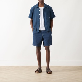 Model wearing Farah Vintage Olsen Textured Shirt in Aegean Blue with matching blue shorts, white tee and tan sandals.