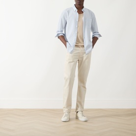 Model wearing Farah Vintage Blue Nickle casual shirt in 100% cotton, styled with cream trousers and white trainers.