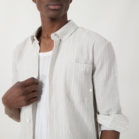 Model wearing Farah Vintage Stone Grey casual shirt in textured cotton, unbuttoned over white vest, with rolled sleeves.