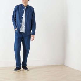 Model wearing Farah Vintage Castle Logo T-Shirt in Blue Nickle, styled with navy overshirt, matching trousers and dark slip-on shoes