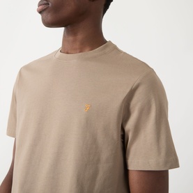 Model wearing Farah Vintage Danny Logo T-Shirt in Stone Grey, crew neck cotton tee with small orange logo embroidery on chest.