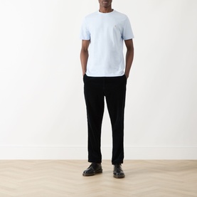Model wearing a pale blue crew neck T-shirt with chest pocket, styled with black trousers and dark leather shoes