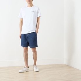 Model wearing Farah Vintage Clissold Logo T-Shirt in white with navy shorts and white trainers.