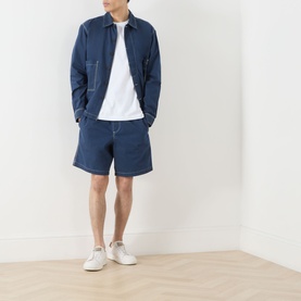 Model wearing Farah Vintage Clissold Logo T-Shirt in White, styled with navy zip jacket, navy shorts, and white trainers.