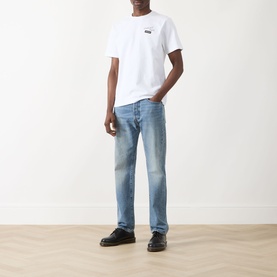 Model wearing Farah Vintage Logo Back Graphic T-Shirt in white with light wash jeans and black shoes.