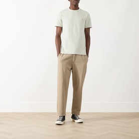 Model wearing Farah Vintage Danny Logo T-Shirt in Soft Green with beige chinos and black canvas trainers.