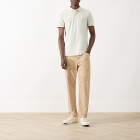 Model wearing Farah Vintage Blanes Logo Polo Shirt in Soft Green with beige chinos and white trainers.
