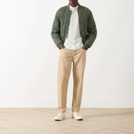 Model wearing Farah Vintage Blanes Logo Polo Shirt in Soft Green, styled with olive quilted bomber jacket and tan chinos.