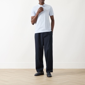 Model wearing Farah Vintage Blanes Logo Polo Shirt in Blue Nickle with navy wide-leg trousers and black loafers.