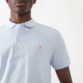 Model wearing Farah Vintage Blanes Logo Polo Shirt in Blue Nickle, short sleeves, polo collar, gold embroidered logo at chest.